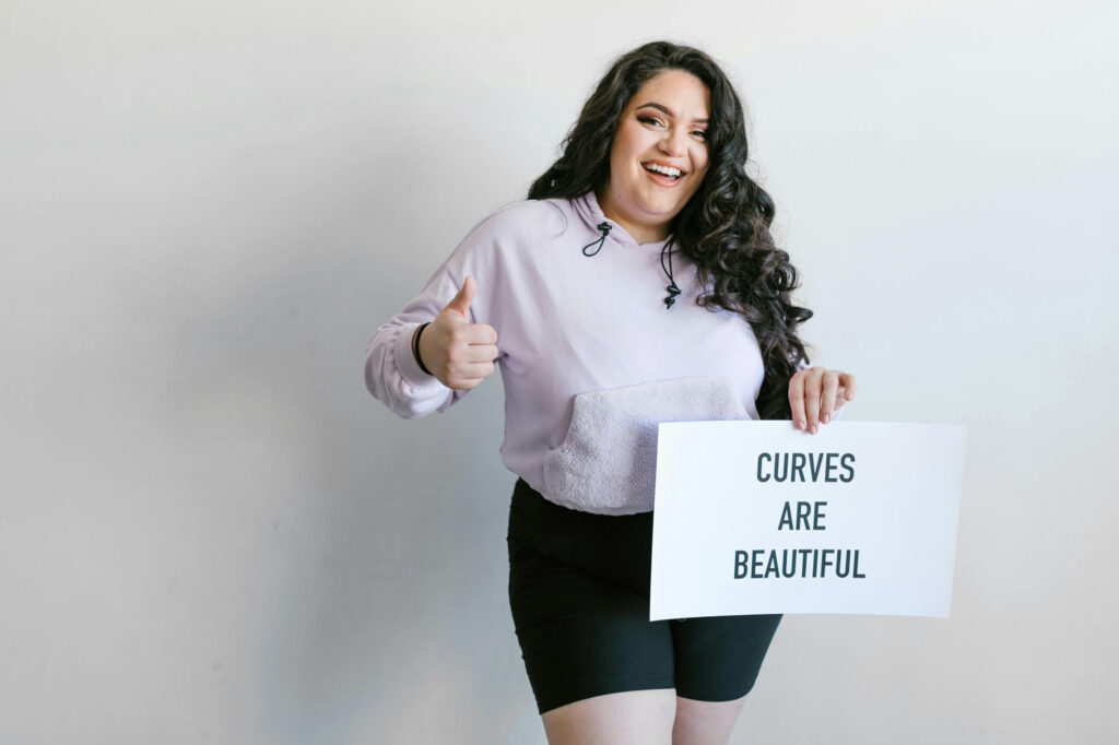 Gorgeous plus size woman holding a sign that says "Curves are beautiful"
