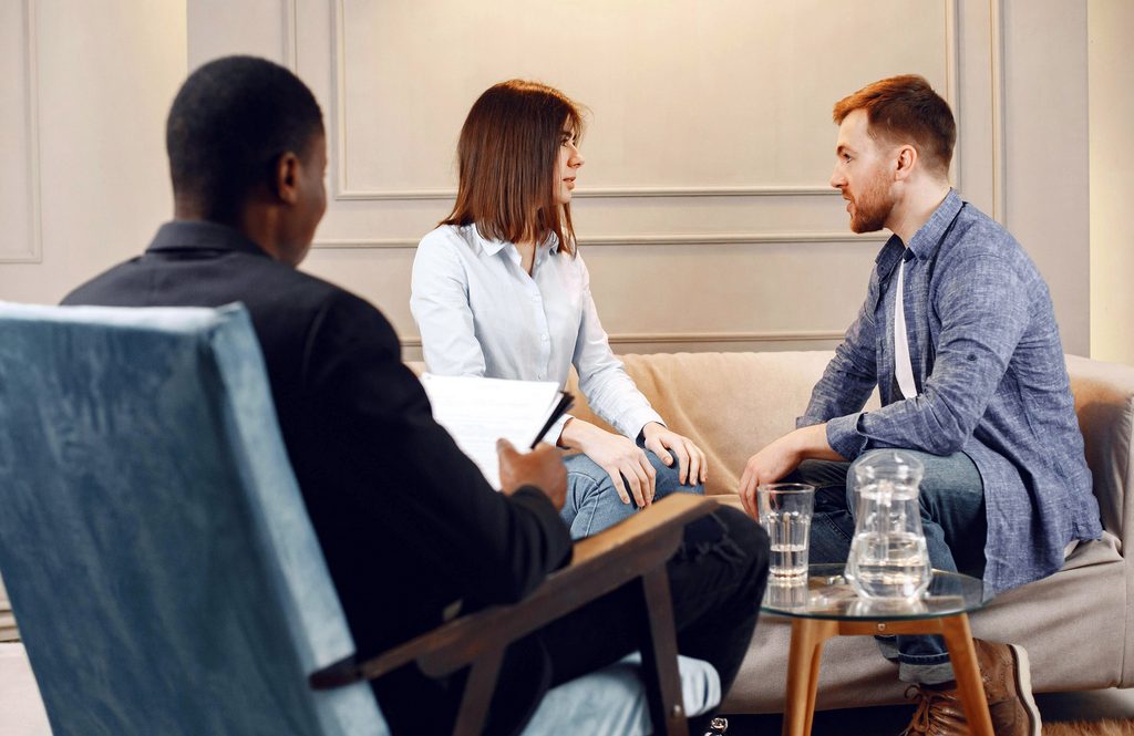 Sex Coach in session with couple working on an intimacy exercise. Everyone is clothed.
