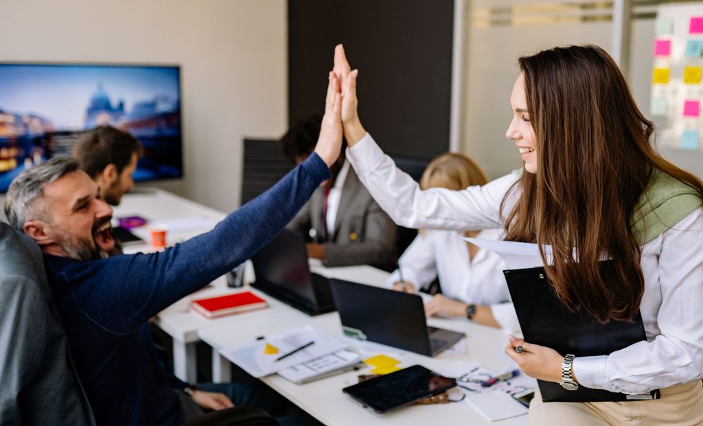 Female leader with emotional intelligence skills high-fiving her male employee