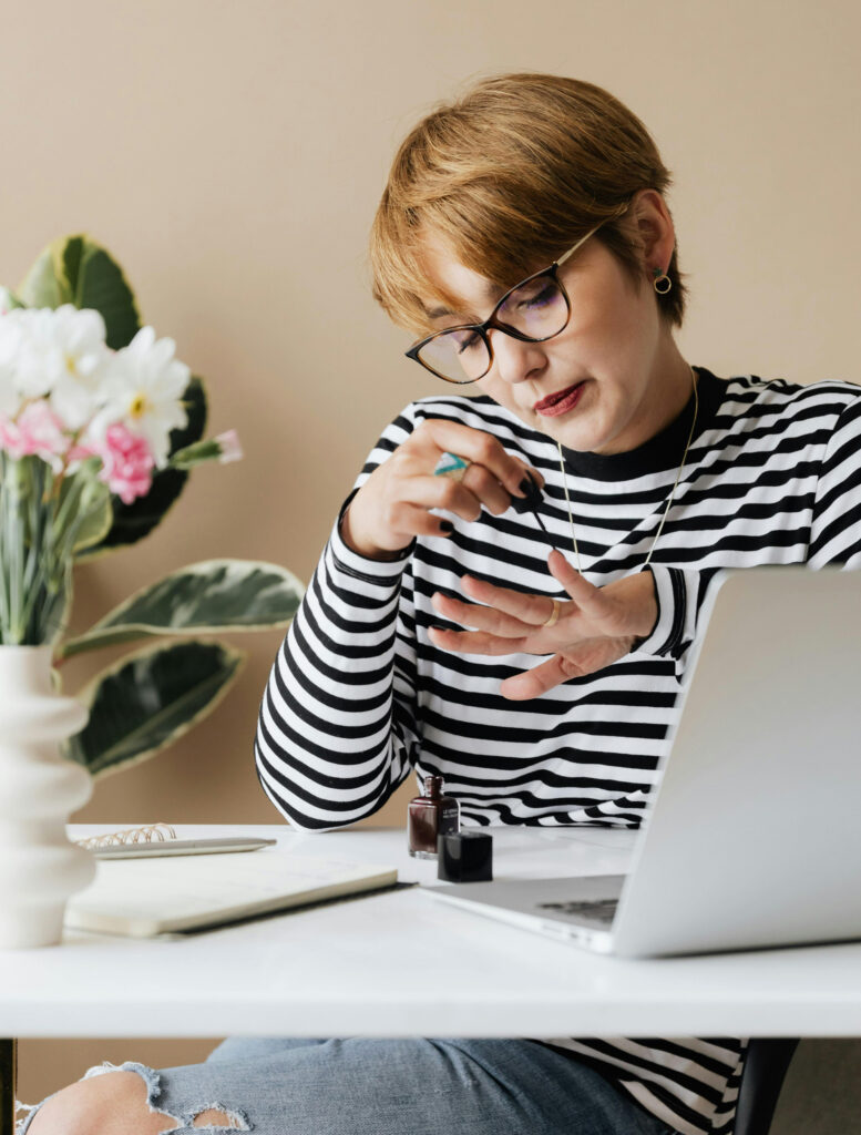 Woman painting her nails while listening to an online passive learning program.