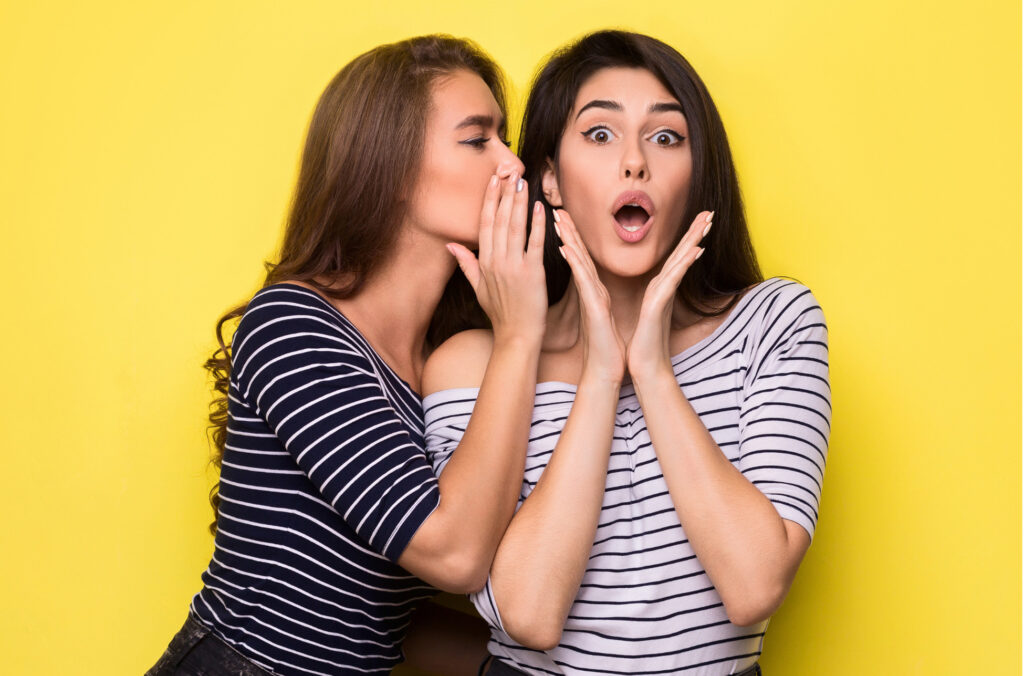 Woman whispering sex coaching myths into her friend's ear