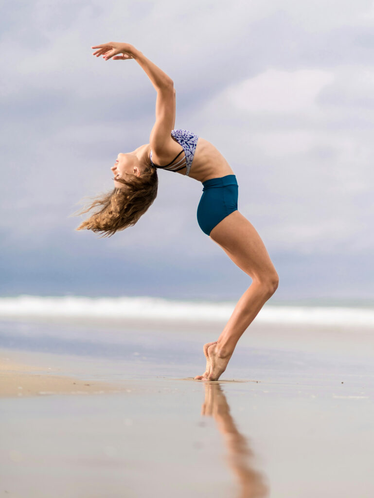 Woman practicing somatic movement on a beach