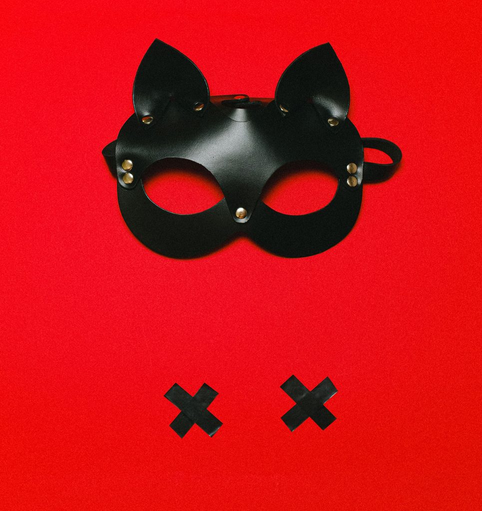 Kinky black leather mask and two black xs on red background